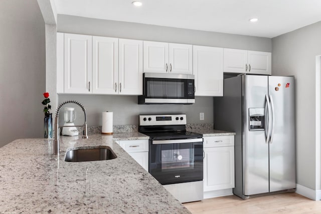 kitchen with sink, stainless steel appliances, white cabinetry, and light stone countertops