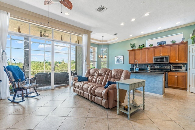 tiled living room with a textured ceiling, ceiling fan, crown molding, and sink