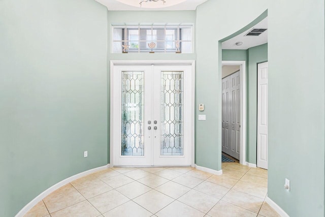 tiled entrance foyer with french doors and a chandelier