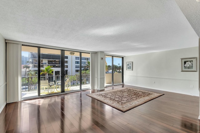 spare room with hardwood / wood-style flooring, a wall of windows, and a textured ceiling