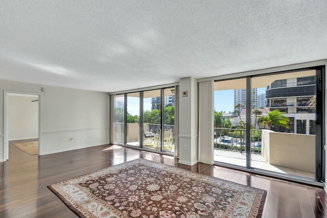 unfurnished room with a textured ceiling, dark hardwood / wood-style floors, and expansive windows