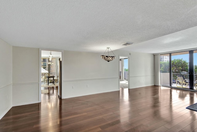 spare room featuring a textured ceiling, expansive windows, and dark hardwood / wood-style floors