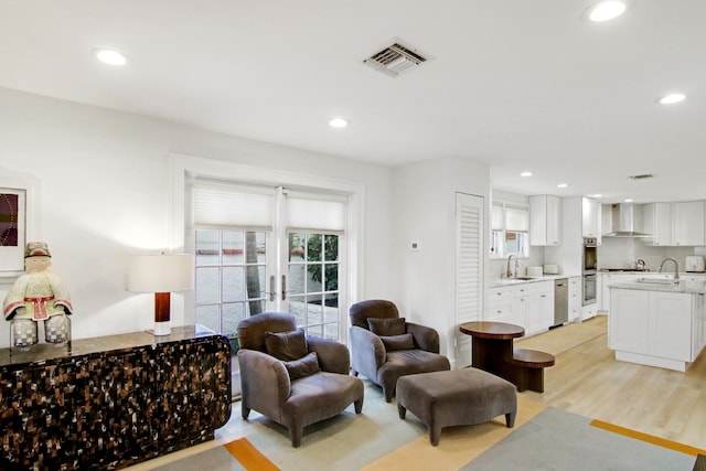 living room featuring sink and light hardwood / wood-style flooring