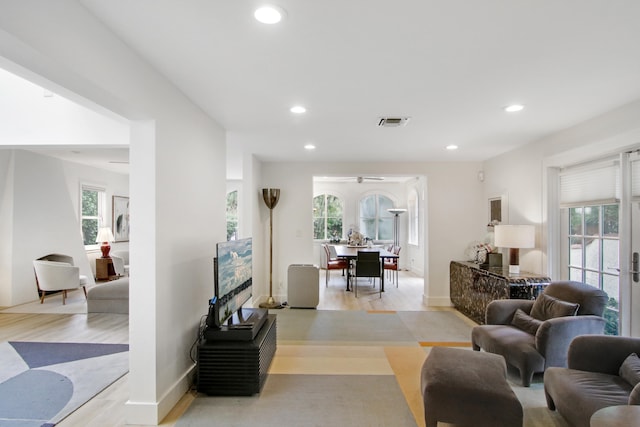 living room featuring light wood-type flooring, plenty of natural light, and ceiling fan