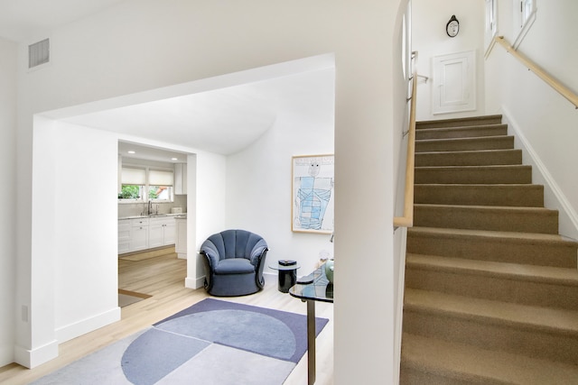 stairs with hardwood / wood-style floors and sink