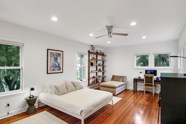 bedroom with hardwood / wood-style floors, ceiling fan, and multiple windows