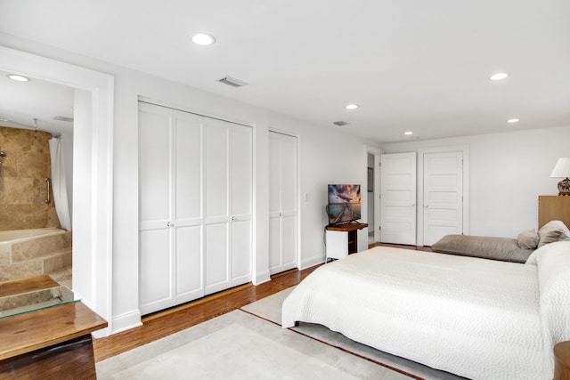 bedroom with multiple closets and hardwood / wood-style floors