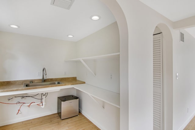 bar featuring light hardwood / wood-style floors and sink