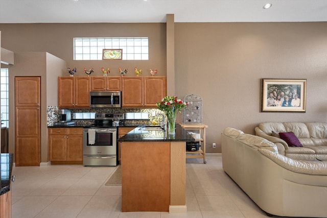 kitchen with light tile patterned flooring, sink, backsplash, and appliances with stainless steel finishes