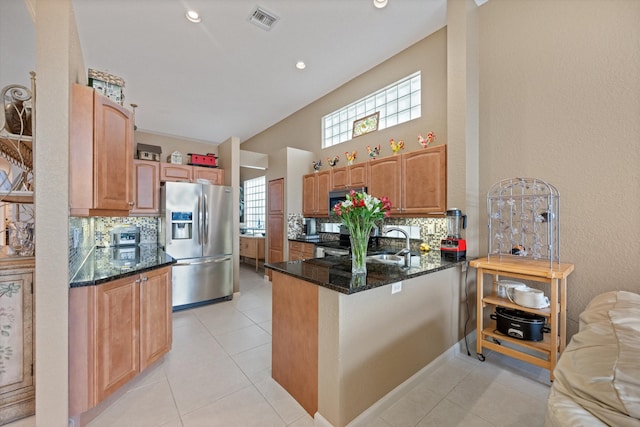 kitchen featuring kitchen peninsula, backsplash, dark stone counters, stainless steel appliances, and light tile patterned flooring