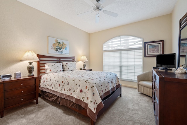 bedroom featuring ceiling fan, light colored carpet, and a textured ceiling