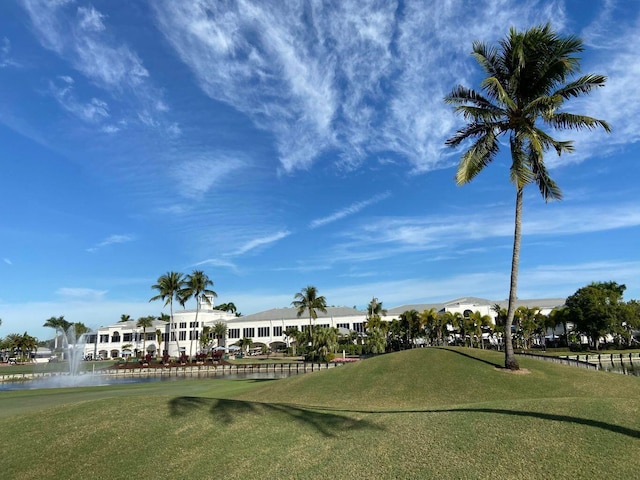 surrounding community with a water view and a lawn