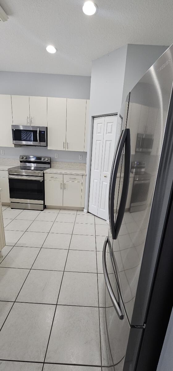 kitchen featuring appliances with stainless steel finishes, a textured ceiling, and light tile patterned flooring