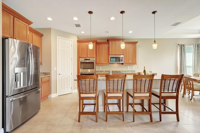 kitchen with pendant lighting, light tile patterned floors, appliances with stainless steel finishes, a kitchen breakfast bar, and light stone countertops