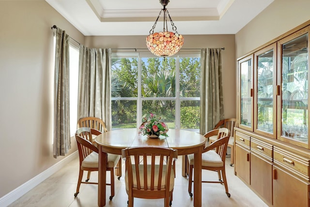 tiled dining space featuring ornamental molding, plenty of natural light, and a raised ceiling