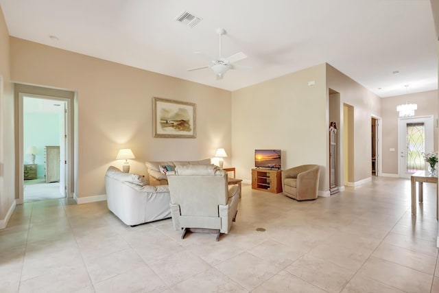 tiled living room with ceiling fan with notable chandelier