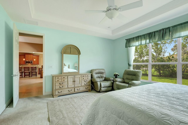 bedroom with ceiling fan, a tray ceiling, and light colored carpet