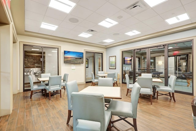 dining area with french doors, hardwood / wood-style flooring, and a drop ceiling