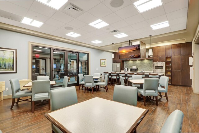 dining space with wood-type flooring and a drop ceiling