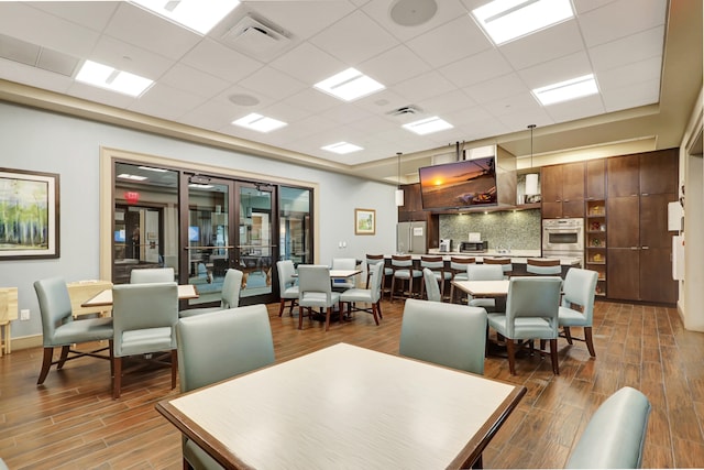 dining room featuring hardwood / wood-style flooring and a drop ceiling