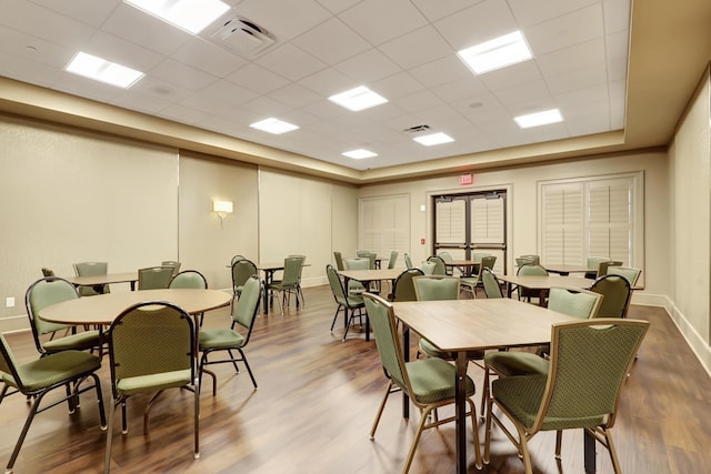 dining area with a drop ceiling and wood-type flooring