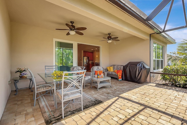 view of patio featuring ceiling fan, a grill, and glass enclosure