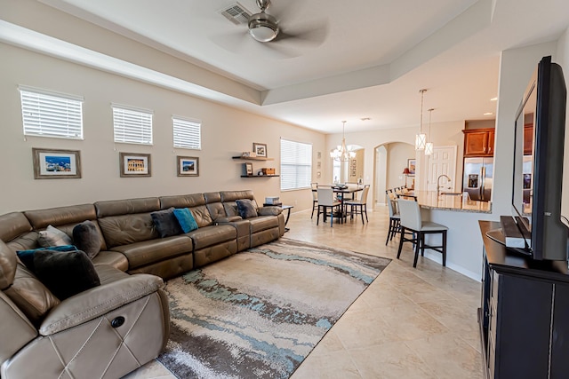 living room featuring ceiling fan with notable chandelier, light tile patterned flooring, and sink