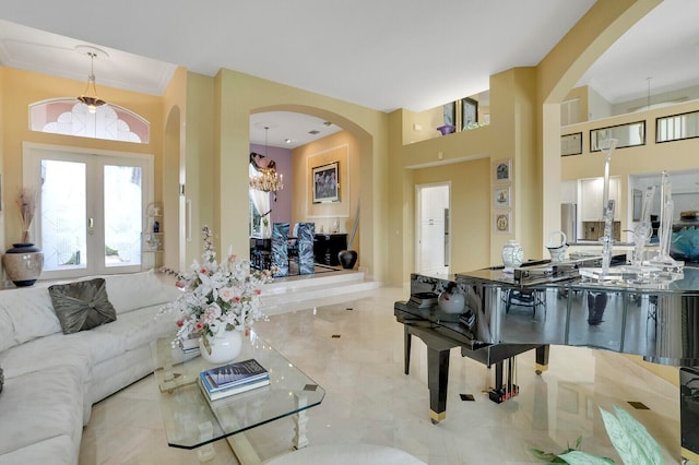 living room featuring a chandelier, a high ceiling, french doors, and ornamental molding