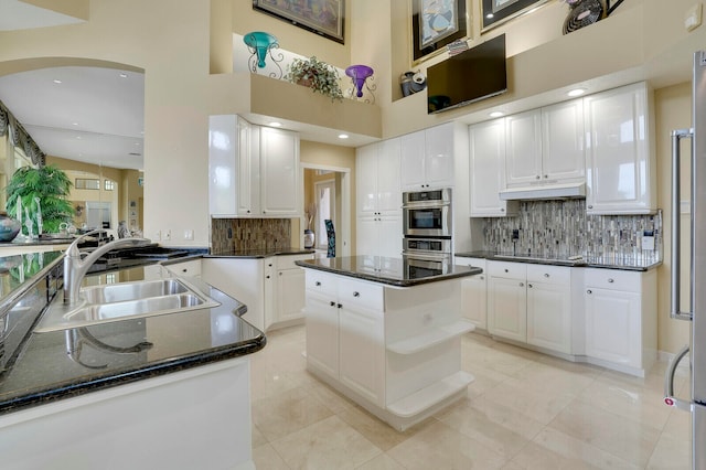 kitchen with a kitchen island, stainless steel double oven, white cabinetry, and sink