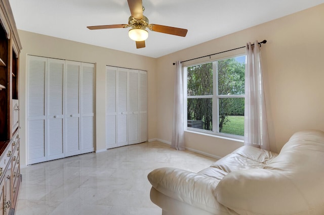 interior space with ceiling fan and two closets