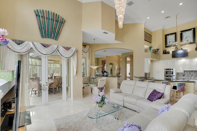 living room featuring crown molding, a high ceiling, and an inviting chandelier