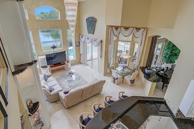 tiled living room featuring a high ceiling and a notable chandelier