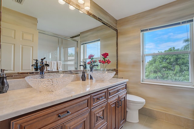 bathroom featuring tile patterned flooring, plenty of natural light, walk in shower, and vanity