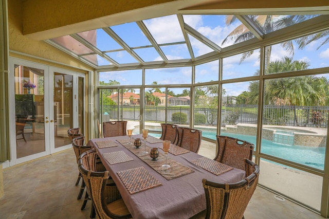 sunroom featuring french doors, a water view, vaulted ceiling, and plenty of natural light