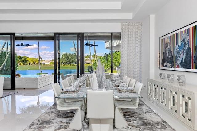 dining space with ceiling fan and a water view