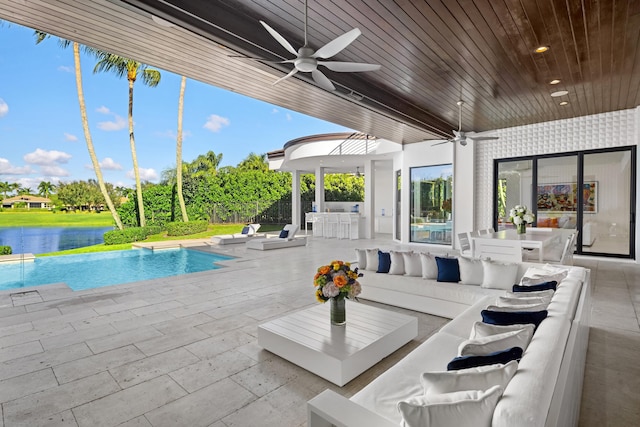 view of patio / terrace with a water view, ceiling fan, a bar, and an outdoor hangout area