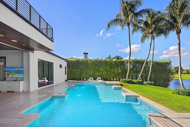 view of pool with an in ground hot tub, a water view, a patio area, and a lawn