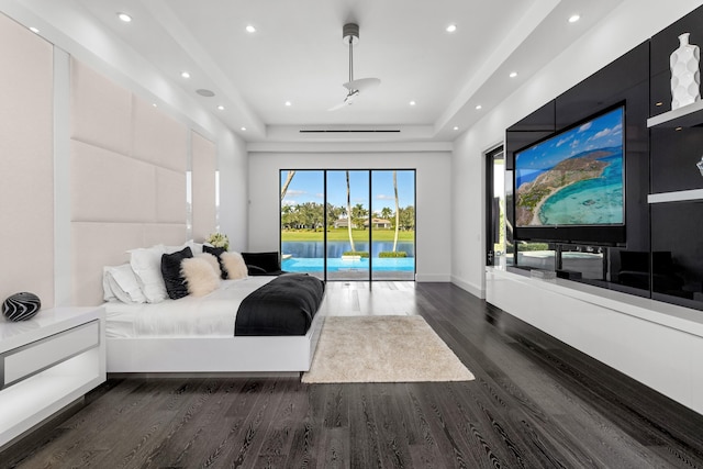 bedroom featuring a raised ceiling, dark hardwood / wood-style floors, and access to exterior