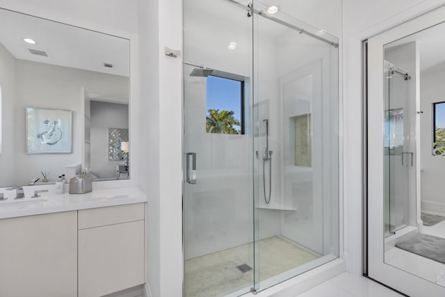 bathroom with tile patterned flooring, vanity, and a shower with door