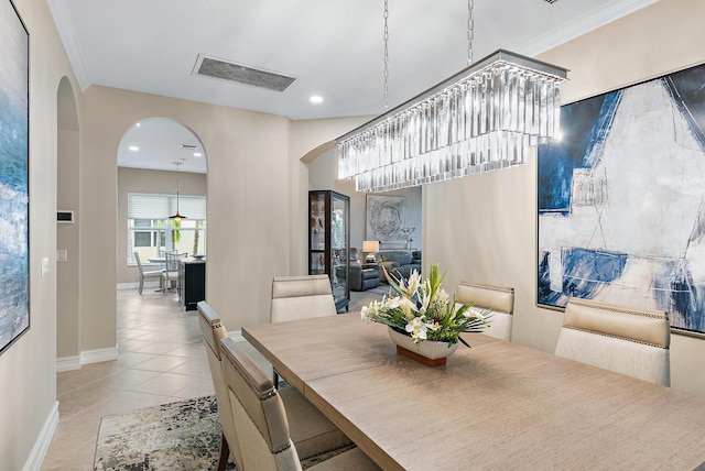 tiled dining room featuring crown molding and a notable chandelier