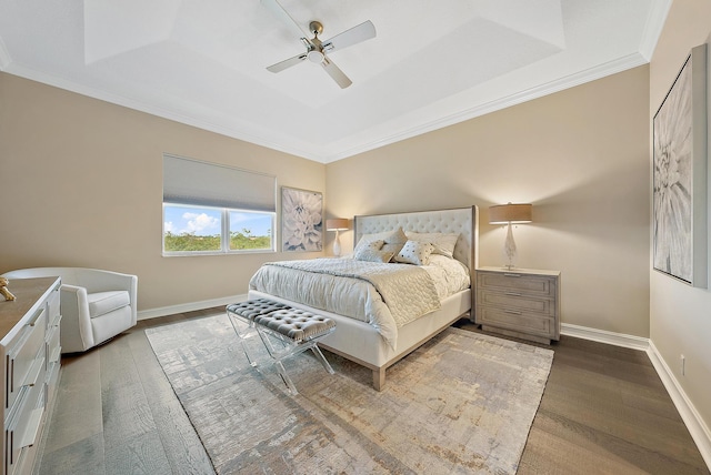 bedroom with ceiling fan, ornamental molding, dark wood-type flooring, and a tray ceiling