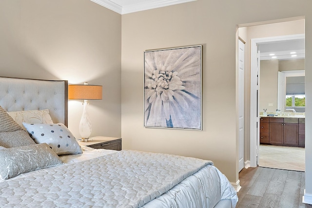 bedroom with hardwood / wood-style flooring, ensuite bath, and ornamental molding