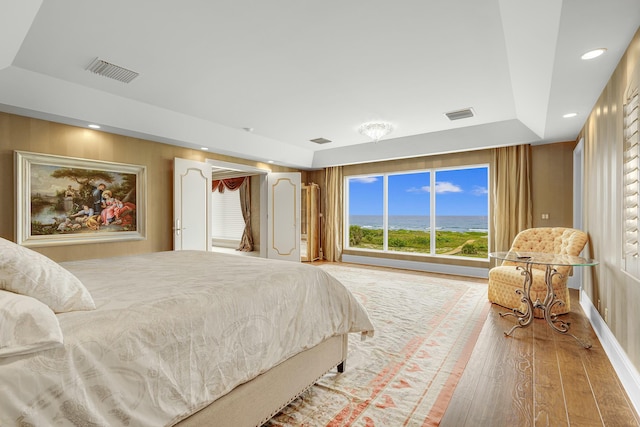 bedroom with hardwood / wood-style floors and a tray ceiling