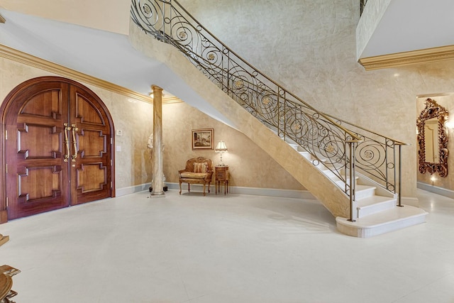 477 S Beach Rd, Jupiter Island, FL 33455 - foyer entrance with stairs, a towering ceiling, crown molding, arched walkways, and baseboards