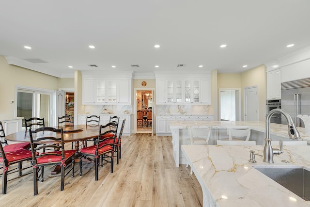 kitchen featuring white cabinets, decorative backsplash, light hardwood / wood-style floors, light stone counters, and stainless steel built in refrigerator