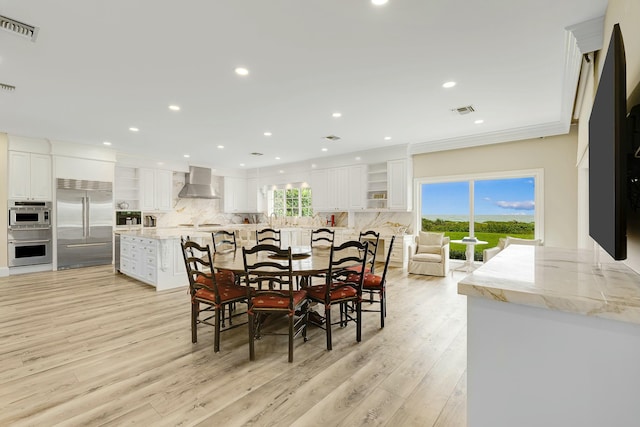 dining room featuring sink, light wood-type flooring, and crown molding