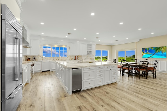 kitchen featuring light wood-type flooring, tasteful backsplash, high quality appliances, a center island, and white cabinetry