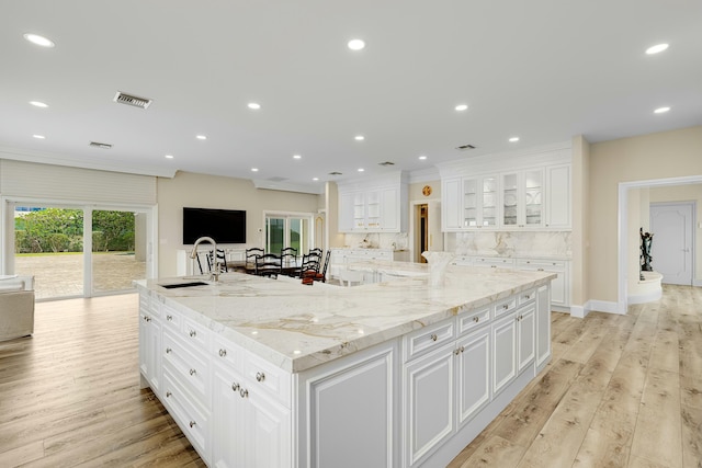 kitchen with a large island with sink, white cabinetry, and light hardwood / wood-style floors