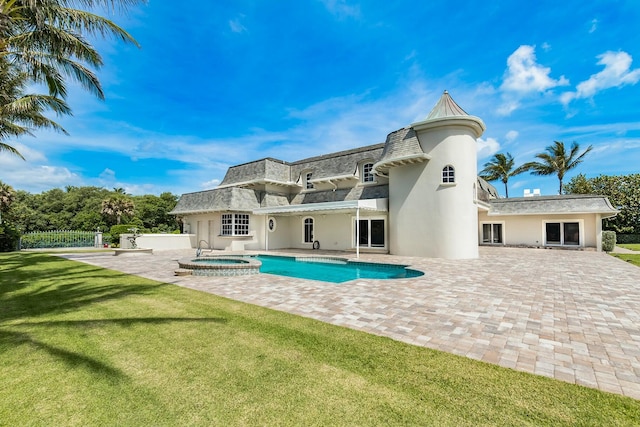 rear view of property with a swimming pool with hot tub, a patio area, and a lawn