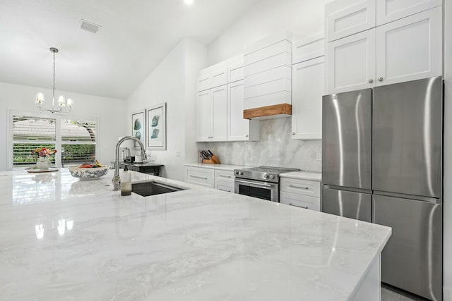 kitchen featuring sink, light stone counters, lofted ceiling, white cabinets, and appliances with stainless steel finishes